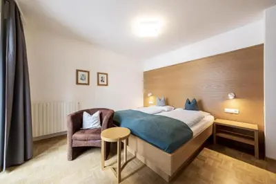 a bedroom with a large bed and a chair at Waldelerhof- Appartements in Meransen in Maranza