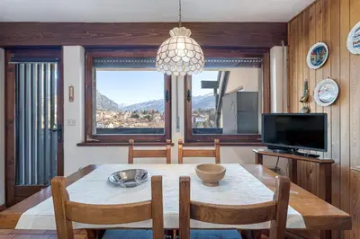 a dining room with a table and chairs and a television at Appartamento Vittoria in Cavalese