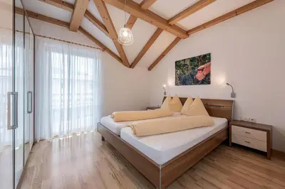 a bedroom with a bed with white walls and wooden floors at Lafoi - Apartments in Eppan in Cornaiano