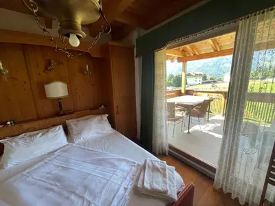 a bedroom with a bed and a balcony with a table at Luxury panoramic apartment Plan de Corones in Tesido