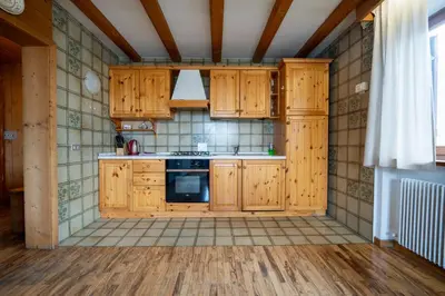 a kitchen with wooden cabinets and a stove at Alpen Suite Apartment in San Vigilio Di Marebbe