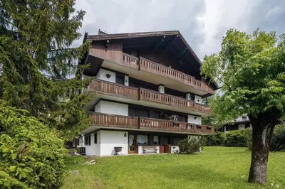 a large building with wooden balconies and a tree at Ca Miramonti - Garden and Tofana view in Cortina dʼAmpezzo