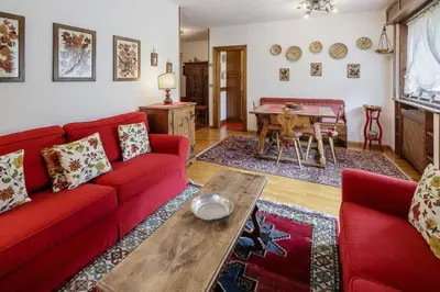 a living room with a red couch and a table at Ca Miramonti - Garden and Tofana view in Cortina dʼAmpezzo
