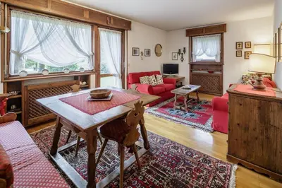 a living room with a table and a red couch at Ca Miramonti - Garden and Tofana view in Cortina dʼAmpezzo