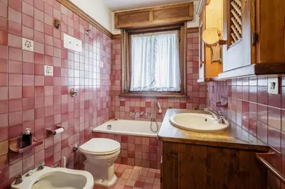 a pink tiled bathroom with a toilet and a sink at Ca Miramonti - Garden and Tofana view in Cortina dʼAmpezzo