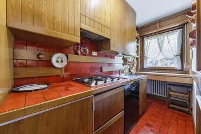 a kitchen with wooden cabinets and a stove top oven at Ca Miramonti - Garden and Tofana view in Cortina dʼAmpezzo