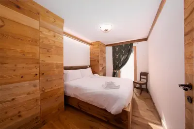 a bedroom with a bed and a wooden wall at Arga' New Alpine Design Apartment Central & Scenic Views in San Vito di Cadore