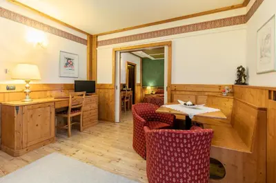 a room with a table and chairs and a desk at G. Hotel Des Alpes (Classic since 1912) in San Martino di Castrozza