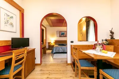 a room with a dining table and a bedroom at G. Hotel Des Alpes (Classic since 1912) in San Martino di Castrozza