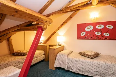 two twin beds in a attic room with wooden beams at G. Hotel Des Alpes (Classic since 1912) in San Martino di Castrozza