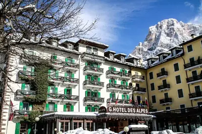 a hotel with a snow covered mountain in the background at G. Hotel Des Alpes (Classic since 1912) in San Martino di Castrozza