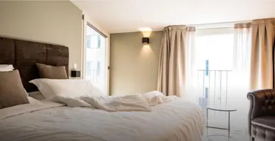 a bedroom with a white bed with a chair and a window at Villa Jasmine in Bolzano