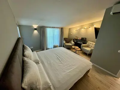 a bedroom with a white bed and a living room at Villa Jasmine in Bolzano