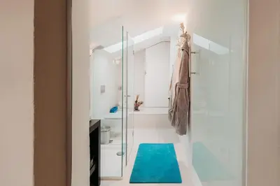 a bathroom with a shower and a blue rug at Loft Thaler Rooms in Bolzano