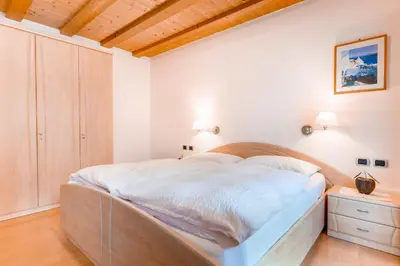 a bedroom with a large bed with a wooden headboard at Residence Villa Toni in San Vigilio Di Marebbe