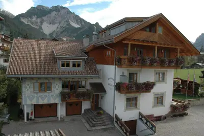 a building with flowers on the balconies of it at Residence Villa Toni in San Vigilio Di Marebbe