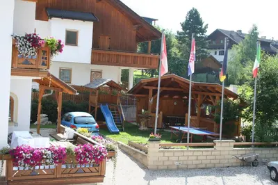 a building with flags and flowers in front of it at Residence Villa Toni in San Vigilio Di Marebbe