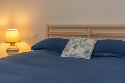 a blue bed with a blue pillow and a lamp at Casa Adriana in Agordo