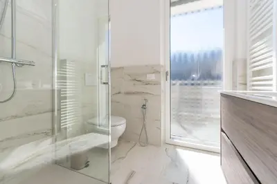 a bathroom with a toilet and a glass shower at Casa Adriana in Agordo