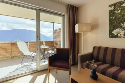 a living room with a couch and a table and a balcony at Hilburger Hotel in Schenna