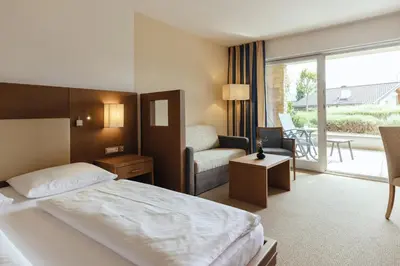 a hotel room with a bed and a chair at Hilburger Hotel in Schenna