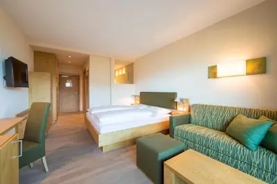 a hotel room with a bed and a couch at Hilburger Hotel in Schenna
