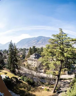 a house on a hill with trees and mountains at Flow Apartments WINKEL ATELIER in Merano