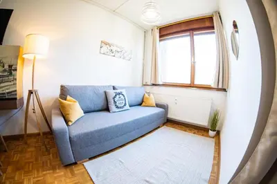 a living room with a blue couch and a window at Flow Apartments WINKEL ATELIER in Merano