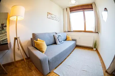 a living room with a blue couch and a window at Flow Apartments WINKEL ATELIER in Merano