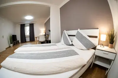 a bedroom with two white beds and a desk at Flow Apartments KIRCHSTEIG in Merano