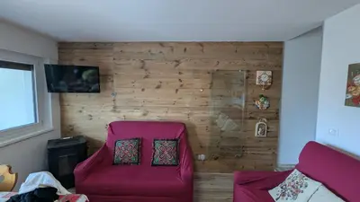 a red chair in a room with a wooden wall at Il Focolare del Cermis in Cavalese