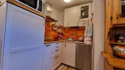 a small kitchen with white cabinets and a microwave at Il Focolare del Cermis in Cavalese