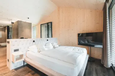 a bedroom with a large white bed and a television at Luxury Spa Suite in Siusi