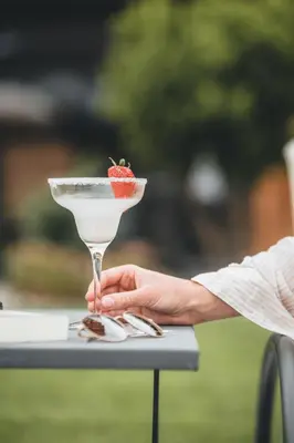 a person holding a martini with a strawberry in it at Luxury Spa Suite in Siusi