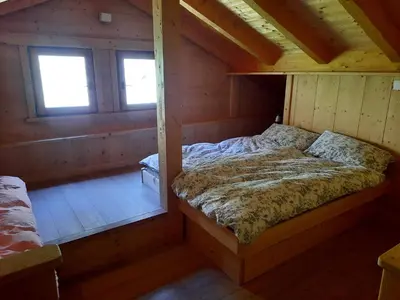 an attic room with a bed and two windows at Tabià Su'n Coi in Alleghe