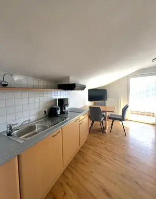 a kitchen with a sink and a table with chairs at Garni Hotel Dorothea in Tirolo