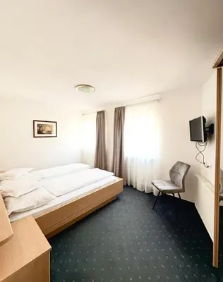 a bedroom with a large bed and a chair at Garni Hotel Dorothea in Tirolo