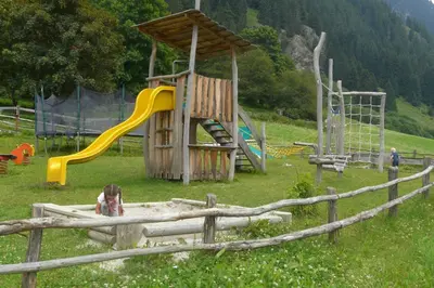 a pond with a fence and mountains in the background at Hotel Larchhof Ratschings in Racines