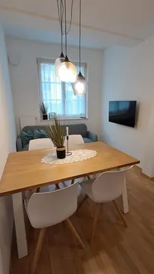 a dining room table with two white chairs and a table with a plant at Villa Trogmann in Merano