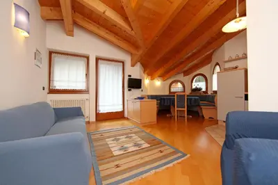 a living room with a blue couch and a kitchen at Cesa Mattias - Appartamenti a Canazei in Canazei