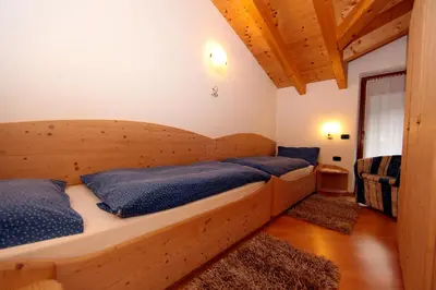 a bedroom with a wooden bed with blue pillows at Cesa Mattias - Appartamenti a Canazei in Canazei
