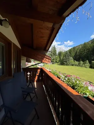 two chairs on a porch with a view of a field at Cesa Mattias - Appartamenti a Canazei in Canazei