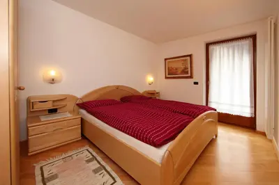 a bedroom with a large bed with a red comforter at Cesa Mattias - Appartamenti a Canazei in Canazei