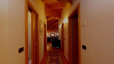 a hallway with wooden ceilings and a hallway with a chair at Cesa Mattias - Appartamenti a Canazei in Canazei