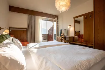 a bedroom with a large bed and a large window at Panorama Hotel St Georgen in Schenna
