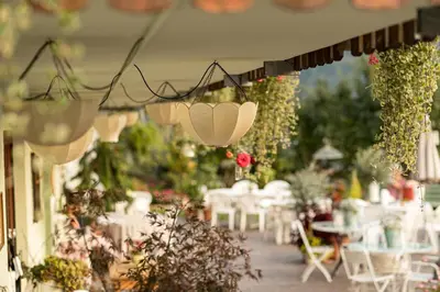 a garden with white chairs and tables and flowers at Panorama Hotel St Georgen in Schenna
