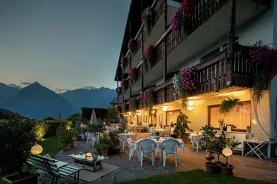a patio with tables and chairs in a building at Panorama Hotel St Georgen in Schenna