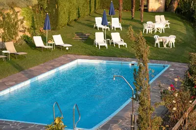 a swimming pool with chairs and tables and umbrellas at Panorama Hotel St Georgen in Schenna