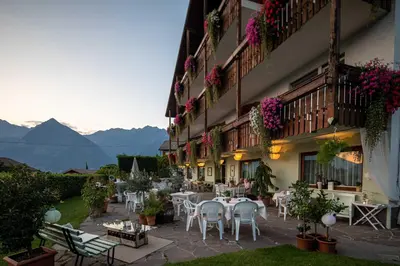 a hotel patio with tables and chairs and flowers at Panorama Hotel St Georgen in Schenna