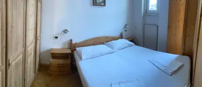 a bedroom with a white bed with a wooden headboard at Appartament Brennero in Colle Isarco